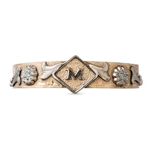 A women's cuff bracelet featuring a personalized initial and silver flower and scrollwork 