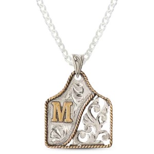 A custom cow tag pendant necklace built on a hand engraved silver base with a bronze initial in the left corner