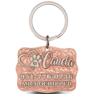 A custom dog tag with personalized engraved silver lettering built on a copper base, featuring a heart and a paw, western designed