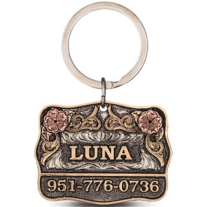 A custom dog tag with personalized engraved bronze lettering built on a matted silver base, featuring copper roses, western designed 